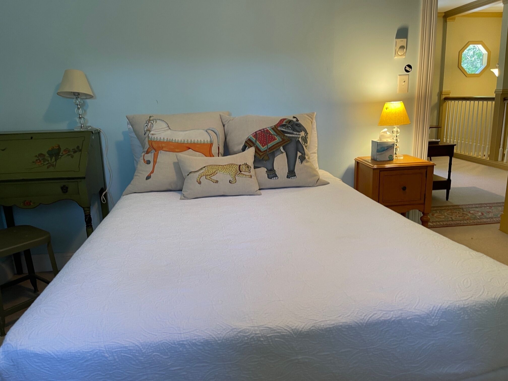 A bed with a white mattress and two decorative pillows featuring animal designs.