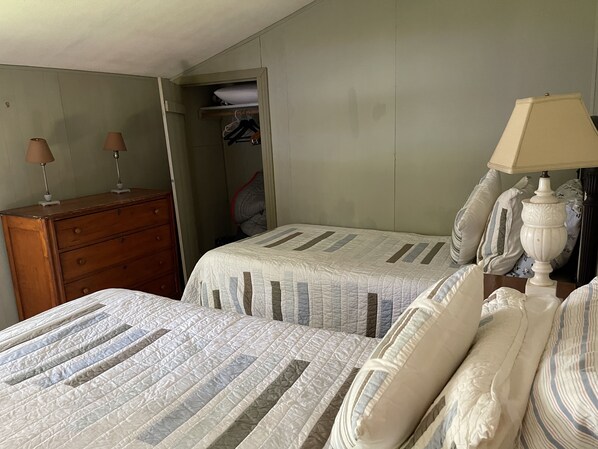A bedroom with two beds, a dresser, a lamp, and a closet.