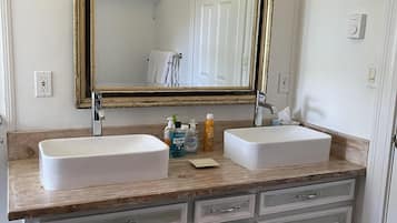 Ein Badezimmer mit zwei Waschbecken, einem großen Spiegel und einer Holzkosmetikschublade.