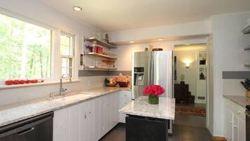A modern kitchen with white cabinets, a granite countertop, a built-in dishwasher, and a refrigerator.