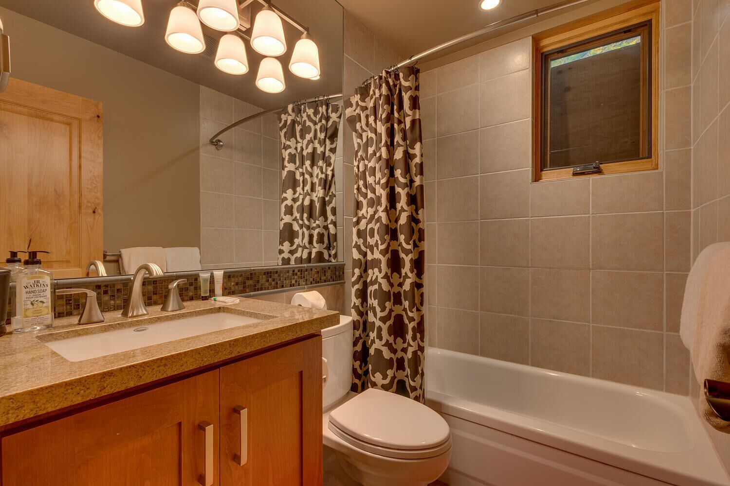 Une salle de bain comprenant un meuble-lavabo, un lavabo, un miroir, une douche et des toilettes.