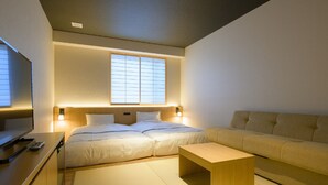 Una habitación de hotel moderna con cama, sofá, una mesita de madera y televisor.