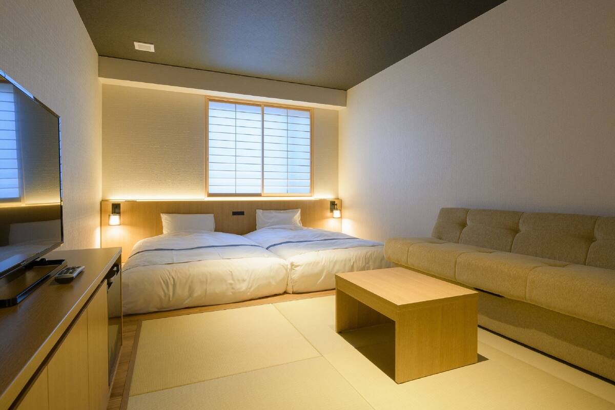 Une chambre d’hôtel moderne équipée d’un lit, d’un canapé, d’une table basse en bois et d’un téléviseur.