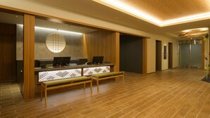 Una zona de recepción con un mostrador de madera, un espejo redondo y un banco.