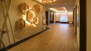 Un pasillo con piso de madera, apliques decorativos y un banco.