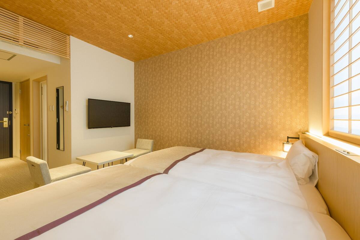 Une chambre d’hôtel avec un grand lit, un téléviseur fixé au mur, une petite table et une chaise.