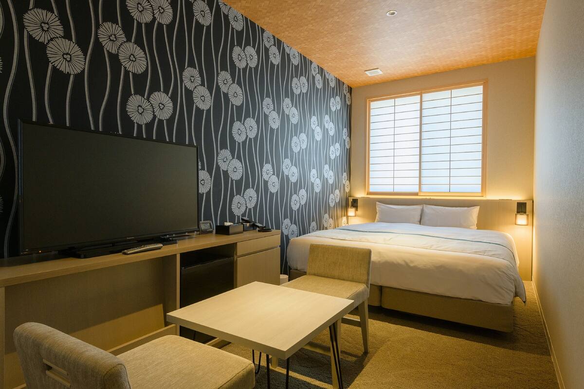 Une chambre d’hôtel avec un lit, une télévision, un bureau et une chaise.