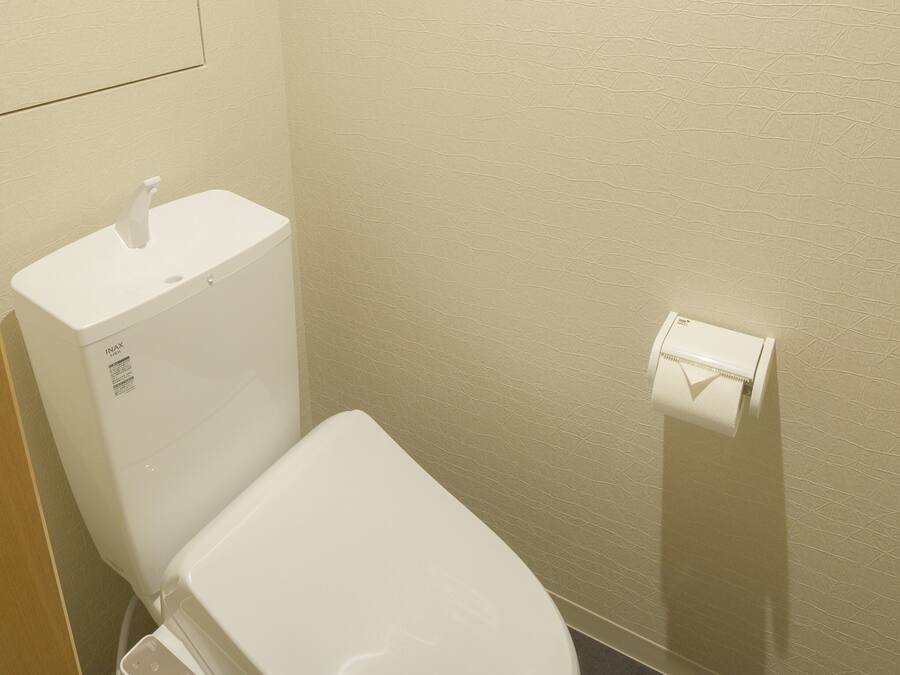 Un baño moderno con inodoro, secamanos y dispensador de toallas de papel.
