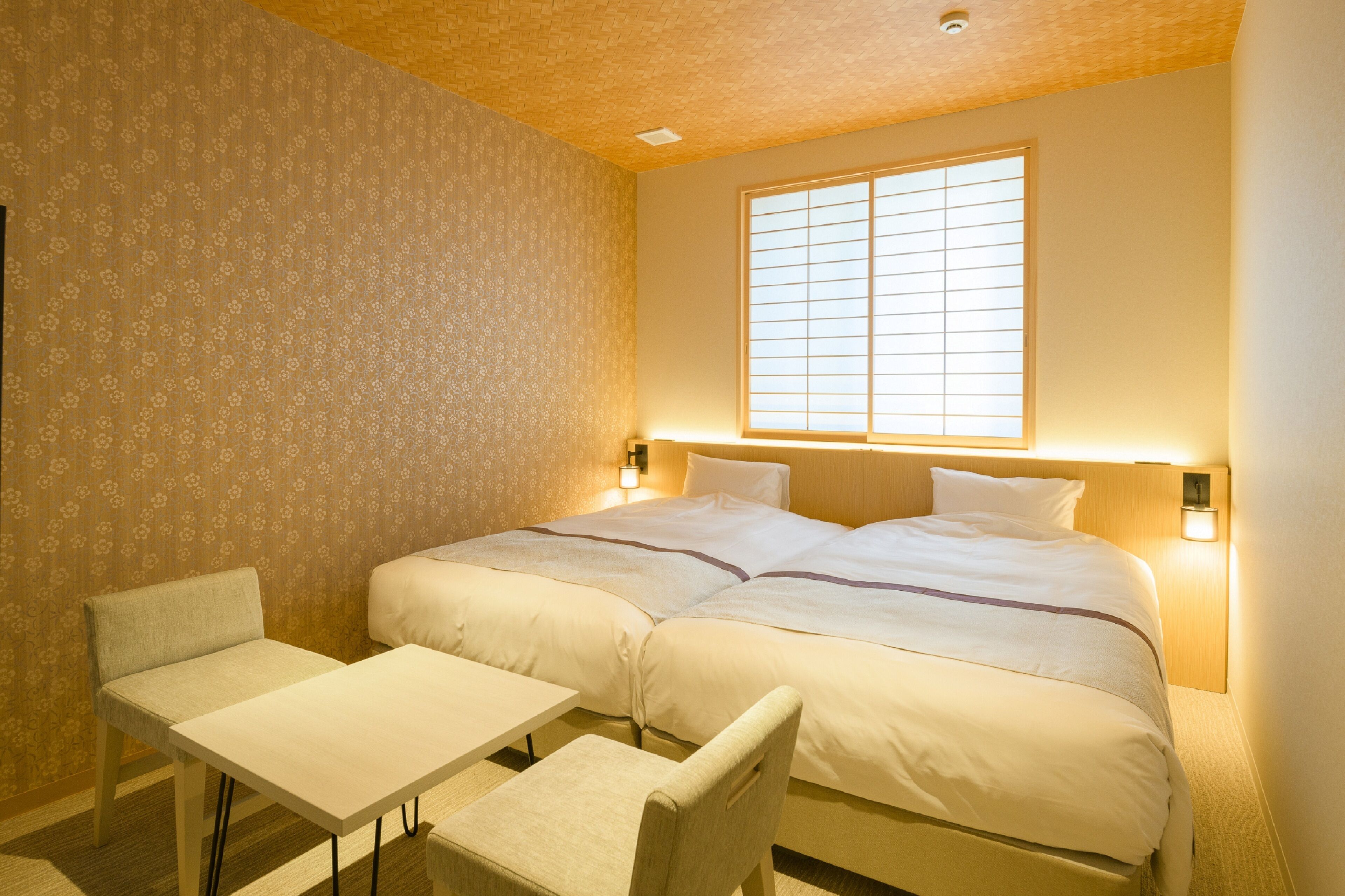 A hotel room with two beds, a small table, and two chairs.