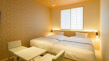 A hotel room with two beds, a small table, and two chairs.