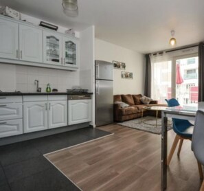 Een moderne keuken met witte kasten, een koelkast en een eethoek met een tafel en stoelen.