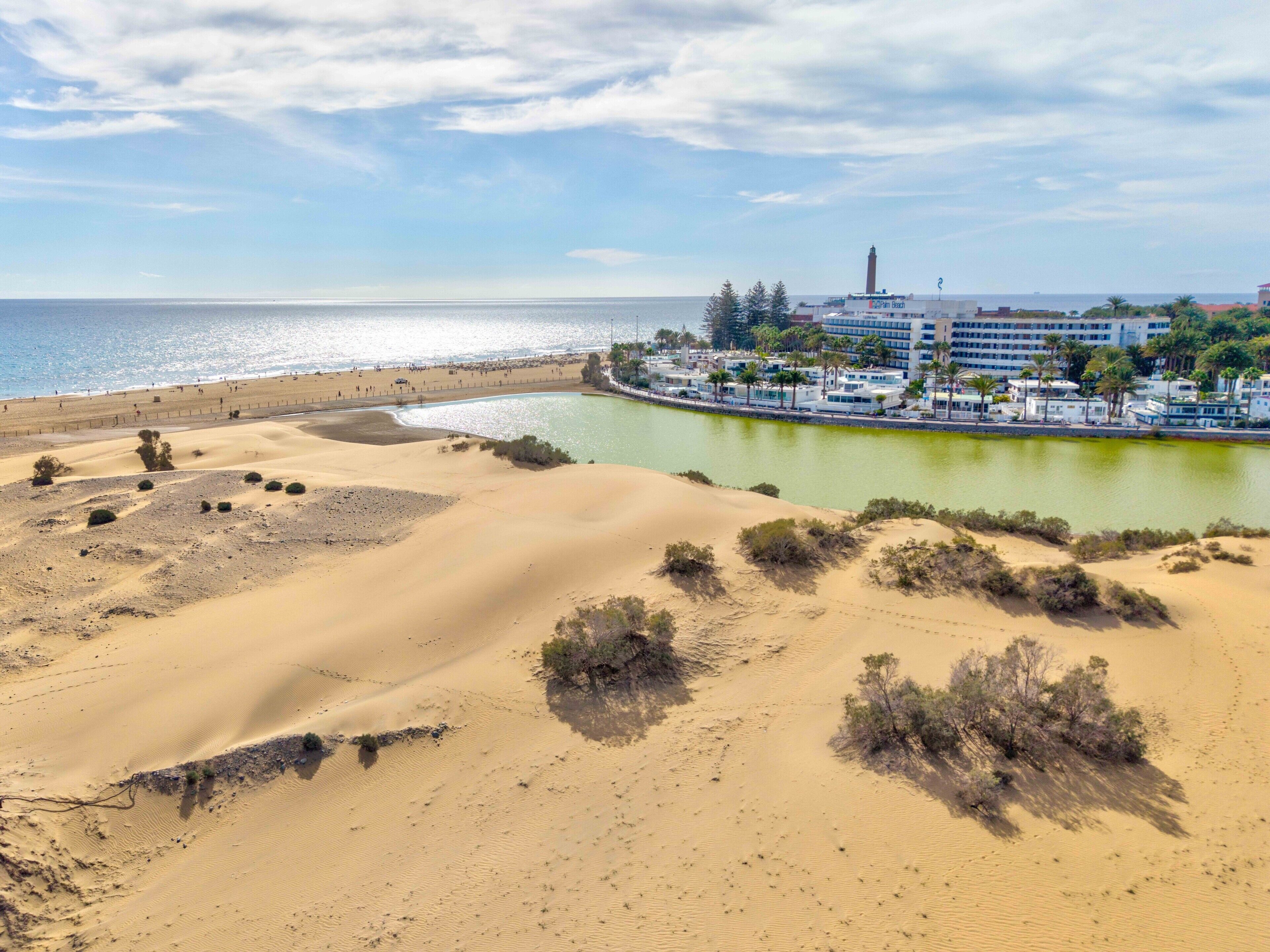 Ein Küstenort mit Sanddünen, einem Strand und einer Marina.