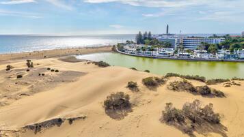 Ein Küstenort mit Sanddünen, einem Strand und einer Marina.