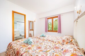 Un dormitorio con cama, ventana con cortinas, espejo y vista al exterior.