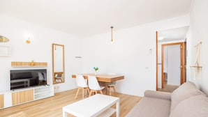 A modern living room with a TV, dining table, chairs, a sofa, and a wooden floor.