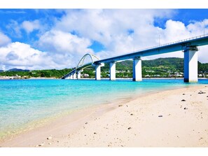 A beach with a large bridge in the background.