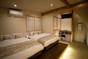 Une chambre de style japonais traditionnel, avec deux lits, une petite salle de bain et un sol recouvert de tatamis.
