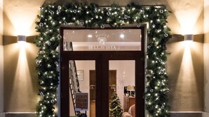 A hotel entrance with a Christmas wreath and lights, a dark wooden door, and a tiled floor. - Hotel Bellavista (Frascati)