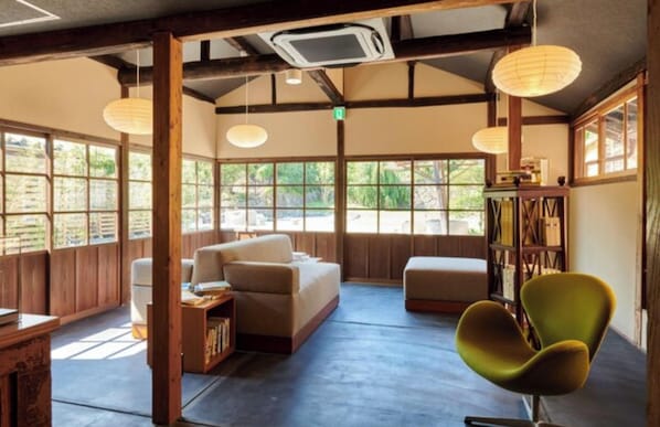 A room with a sofa, a green chair, and a bookshelf.
