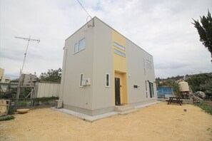 A modern, single-story building with a flat roof, a small entrance, and a visible satellite dish.
