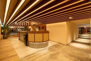 Un'area di accoglienza con una scrivania in legno, una pianta in vaso e un moderno design del soffitto.