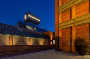 A modern building with a prominent sign, a sloped roof, and a brick facade.
