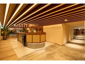 A reception area with a wooden reception desk, a potted plant, and a modern ceiling design. - Deluxe twin room without meals / Fukuoka Fukuoka (Fukuoka)