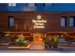 The OneFive Terrace Fukuoka hotel entrance with a wooden facade, outdoor seating, and potted plants.