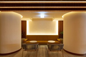 A modern interior with a central seating area, two chairs, and a wall-mounted light.