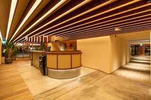 Un'area di accoglienza con una scrivania in legno, una pianta in vaso e un moderno design del soffitto.