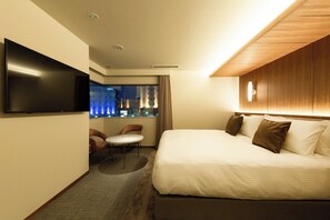 Una habitación de hotel con cama, televisor de pantalla plana, una mesita y una silla.