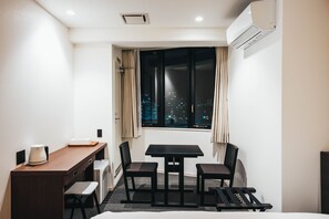 Enjoy a compact room with a single bed, desk, and table with chairs, offering a city view.