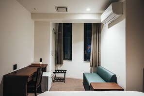 Cozy retreat with a single bed, desk, and sofa, offering a comfortable space to unwind.