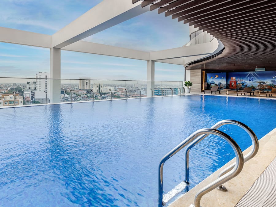 A large indoor swimming pool with a view of the cityscape, a curved ceiling, and a mural on the wall.