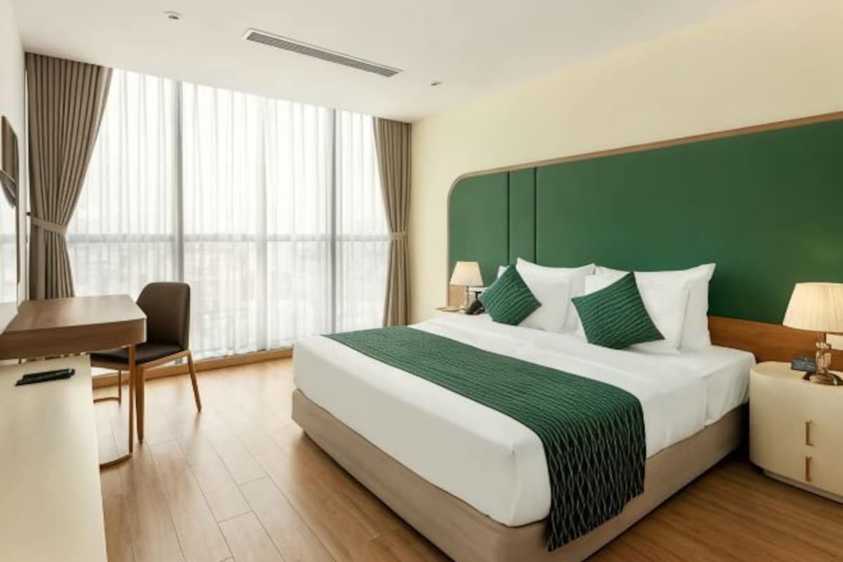 Habitación de hotel con una cama grande, un escritorio, una silla y vistas a la ciudad.