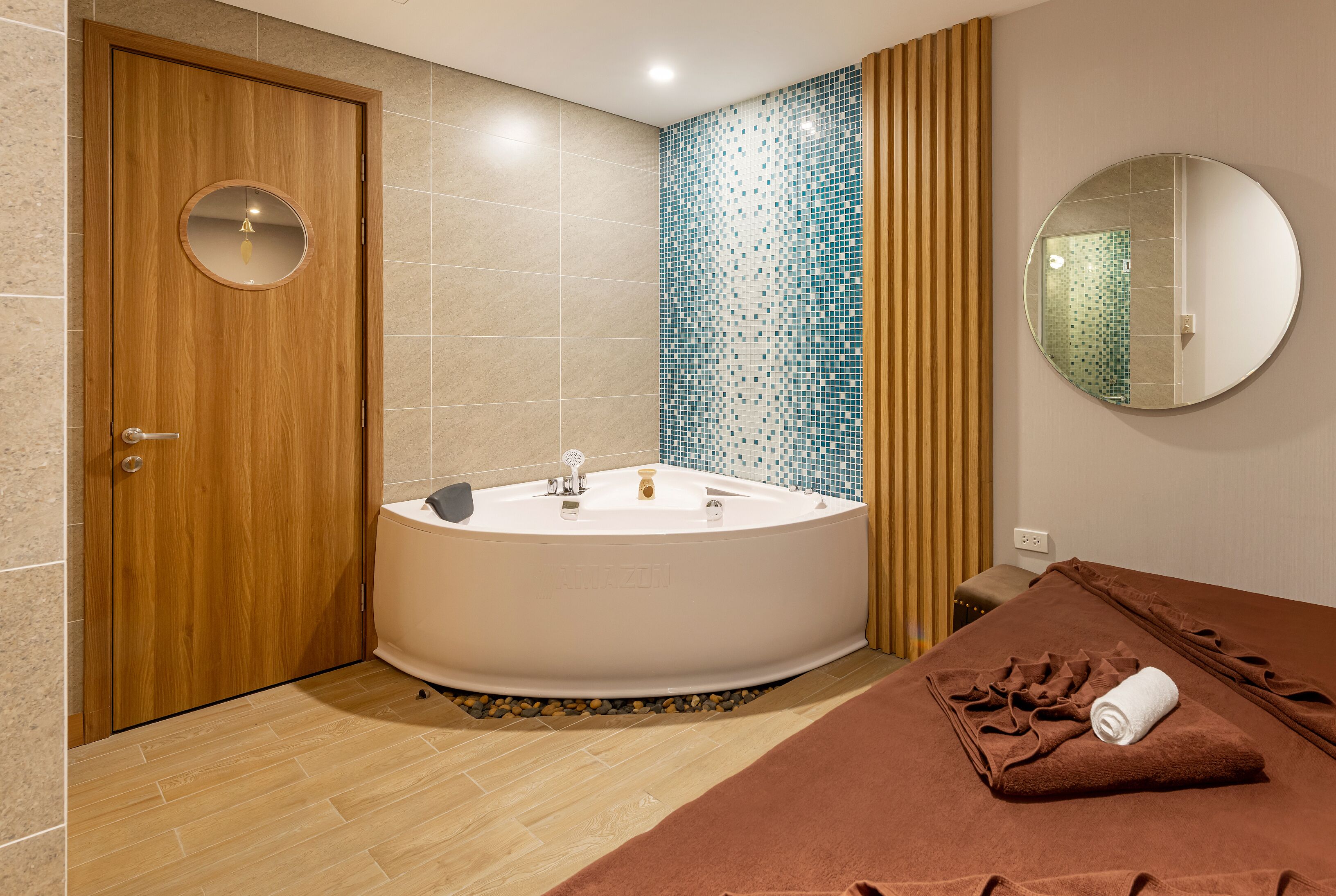 A modern bathroom with a wooden door, a freestanding bathtub, a towel rack, and a mirror on the wall.
