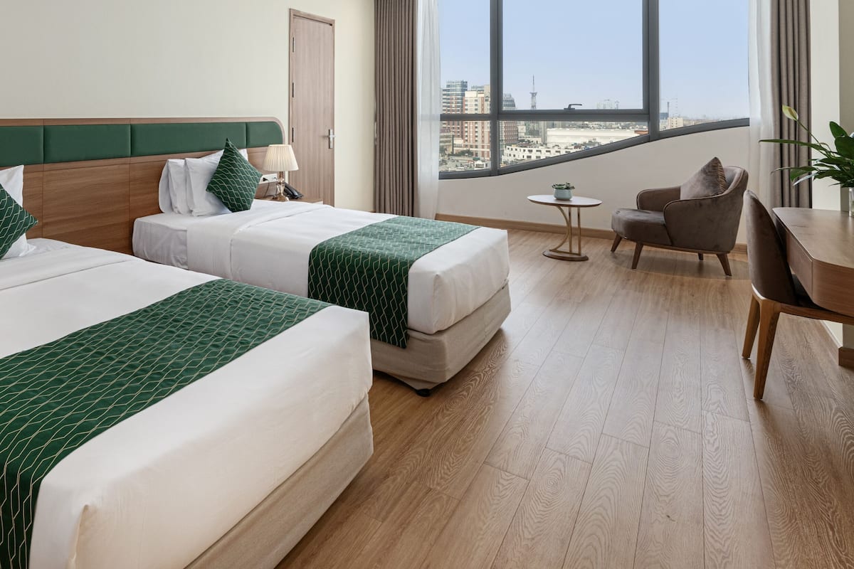 Une chambre d’hôtel avec deux lits, un bureau, une chaise et une vue sur la ville.