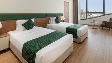 Ein Hotelzimmer mit zwei Betten, einem Schreibtisch, einem Stuhl und Blick auf die Stadt.