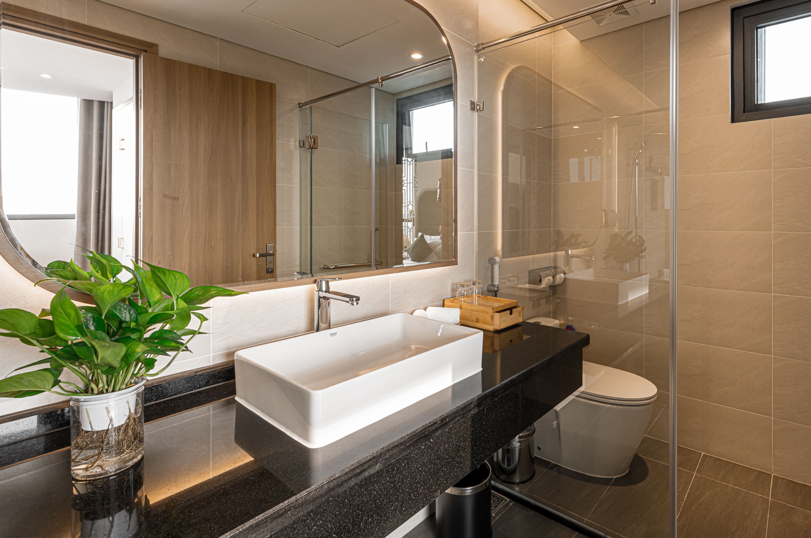 A modern bathroom with a large rectangular sink, a glass shower enclosure, and a toilet.