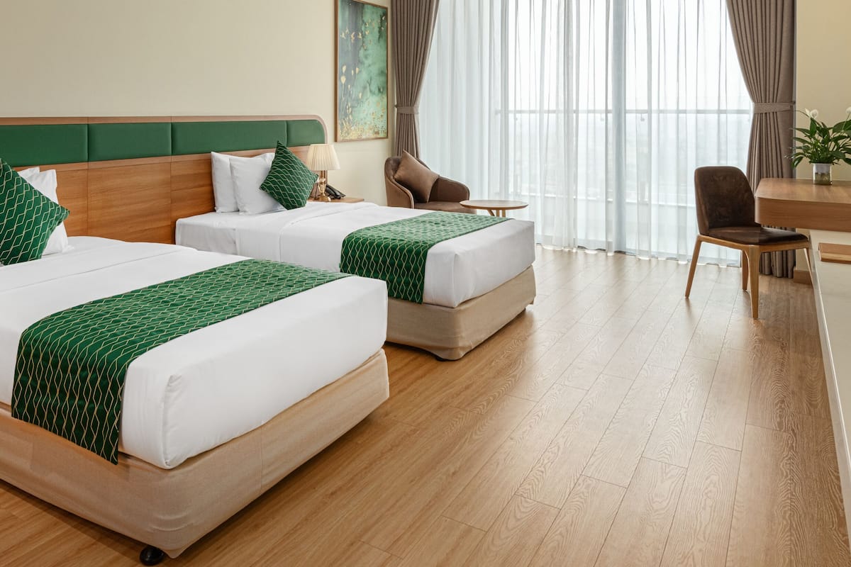 Une chambre d’hôtel avec deux lits, un bureau, une chaise et un téléviseur.