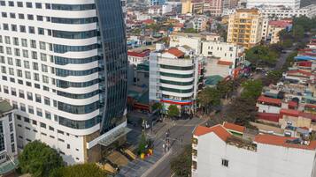 A high-rise building with multiple floors, surrounded by other buildings and a street with a Christmas tree.