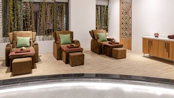 A spa room with three reclining chairs, a wooden cabinet, and a window with bamboo plants.