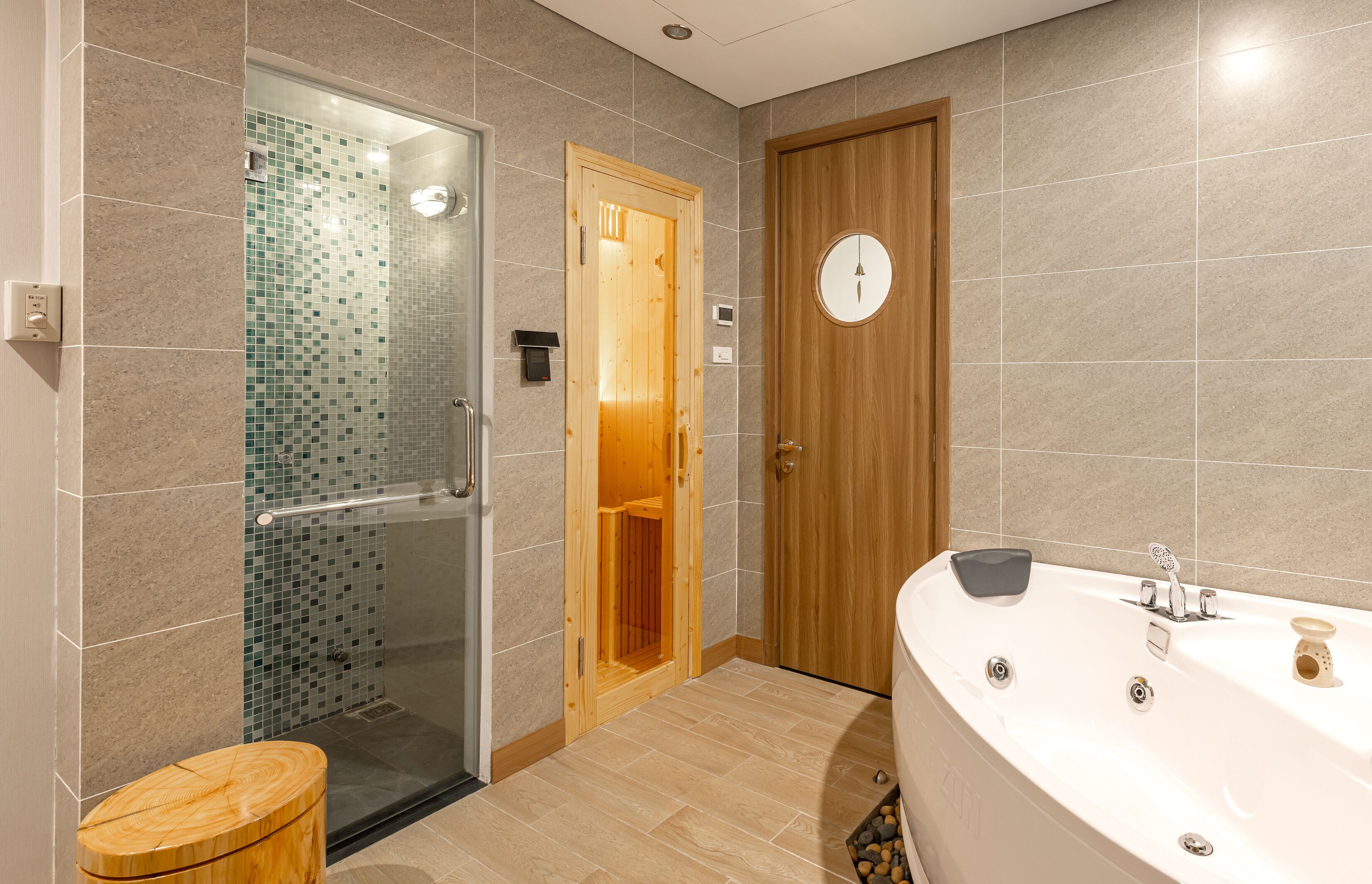Un baño moderno con ducha de vidrio, puerta de madera y una bañera grande.