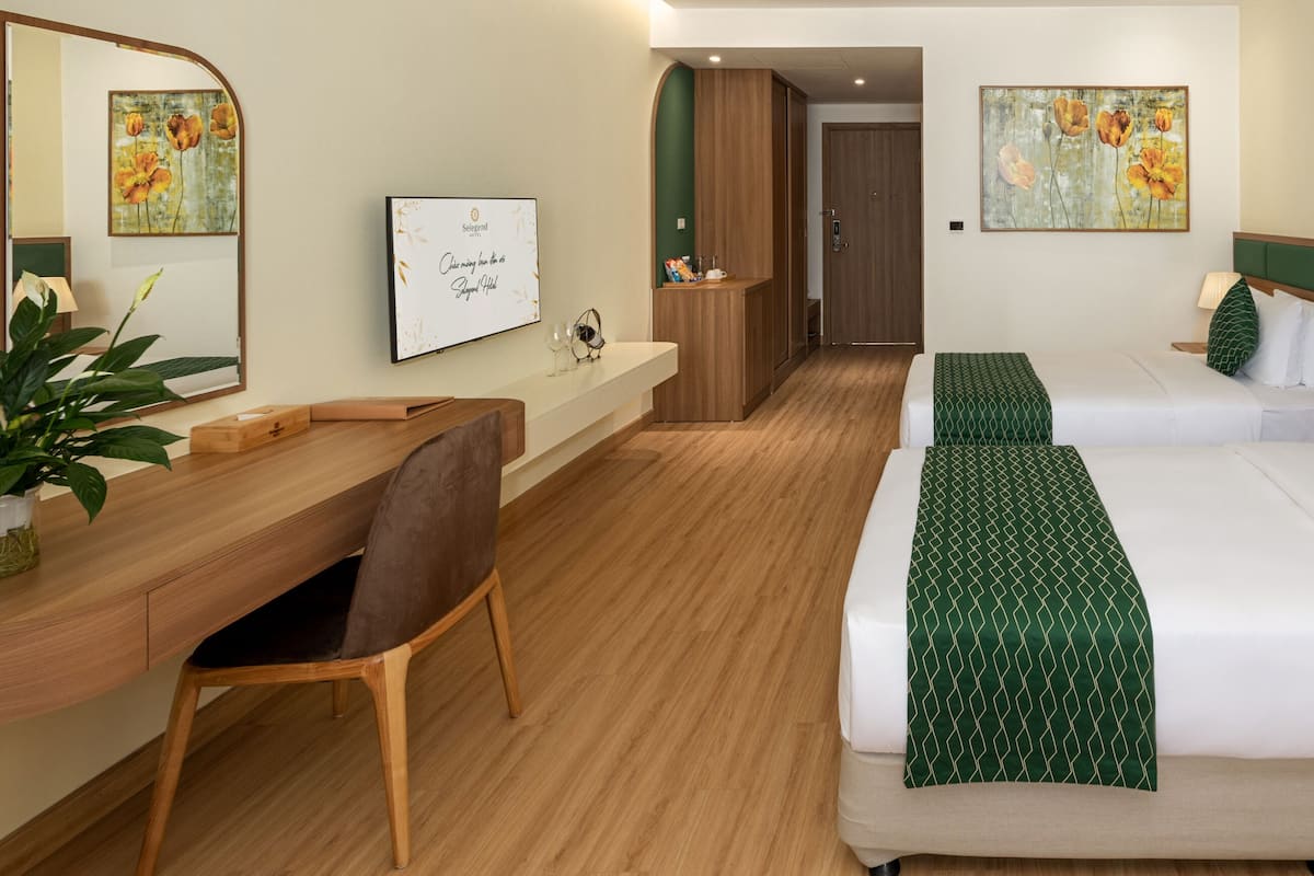 Une chambre d’hôtel avec deux lits, un bureau, une chaise et une petite kitchenette.