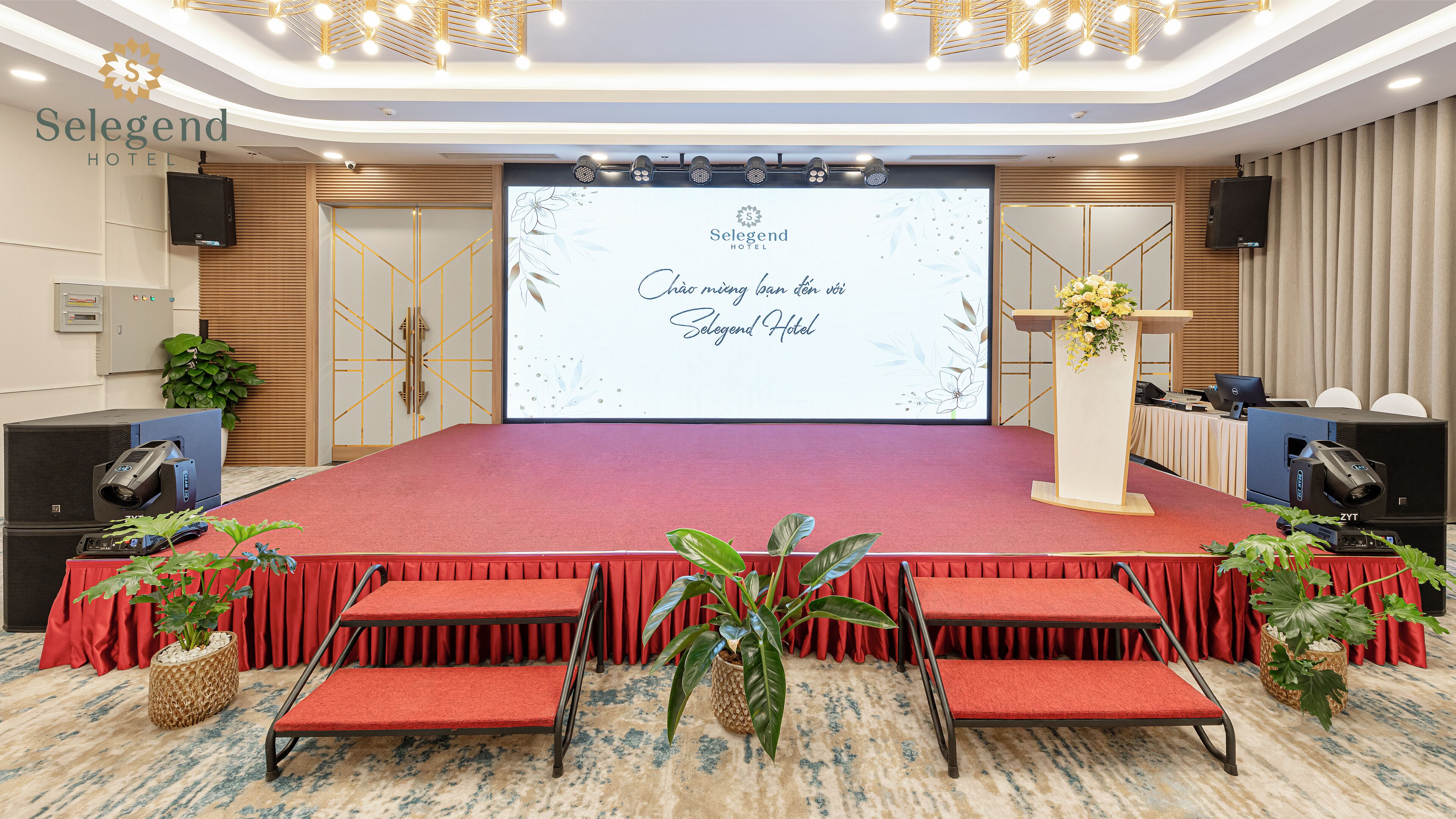 Un salón de conferencias con un escenario, alfombra roja y asientos.