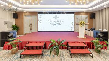Un salón de conferencias con un escenario, alfombra roja y asientos.
