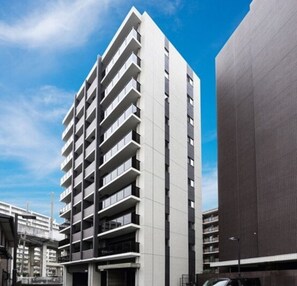 A modern high-rise building with multiple balconies and a flat facade.