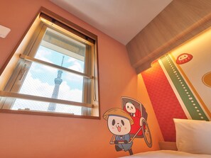 Une chambre d’hôtel avec une grande fenêtre, un lit et un mur décoré de personnages de dessins animés.