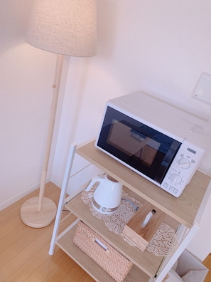 Compact kitchenette with microwave, kettle, and storage.