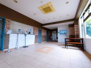 Experience the modern atmosphere of our lobby, featuring a high ceiling, brick and white panel walls, and a digital information kiosk.
